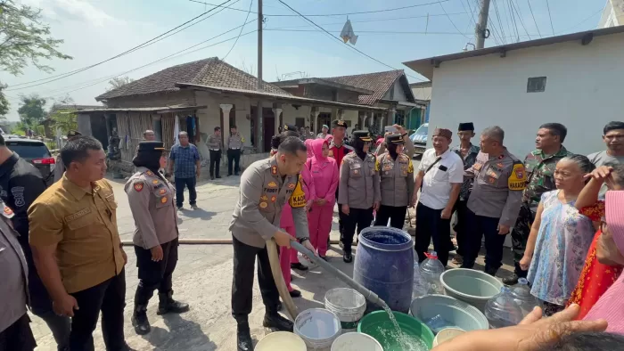 Kapolres Pasuruan AKBP Teddy Candra saat mengisi ember dan bak milik warga (Humas)