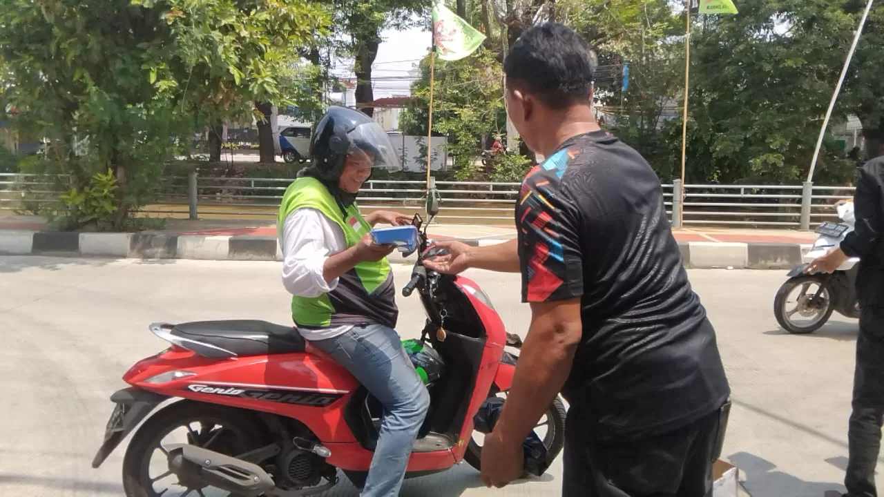Salah satu anggota PWI Bekasi Raya saat memberikan Nasi Kotak Gratis kepada pengemudi Ojol. (PWI Bekasi Raya for BacainD.com)