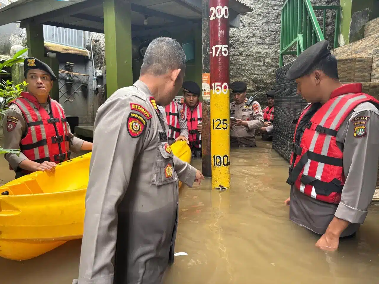 Petugas Kepolisian saat menujukkan tinggi air banjir di Kebon Pala. (hms)