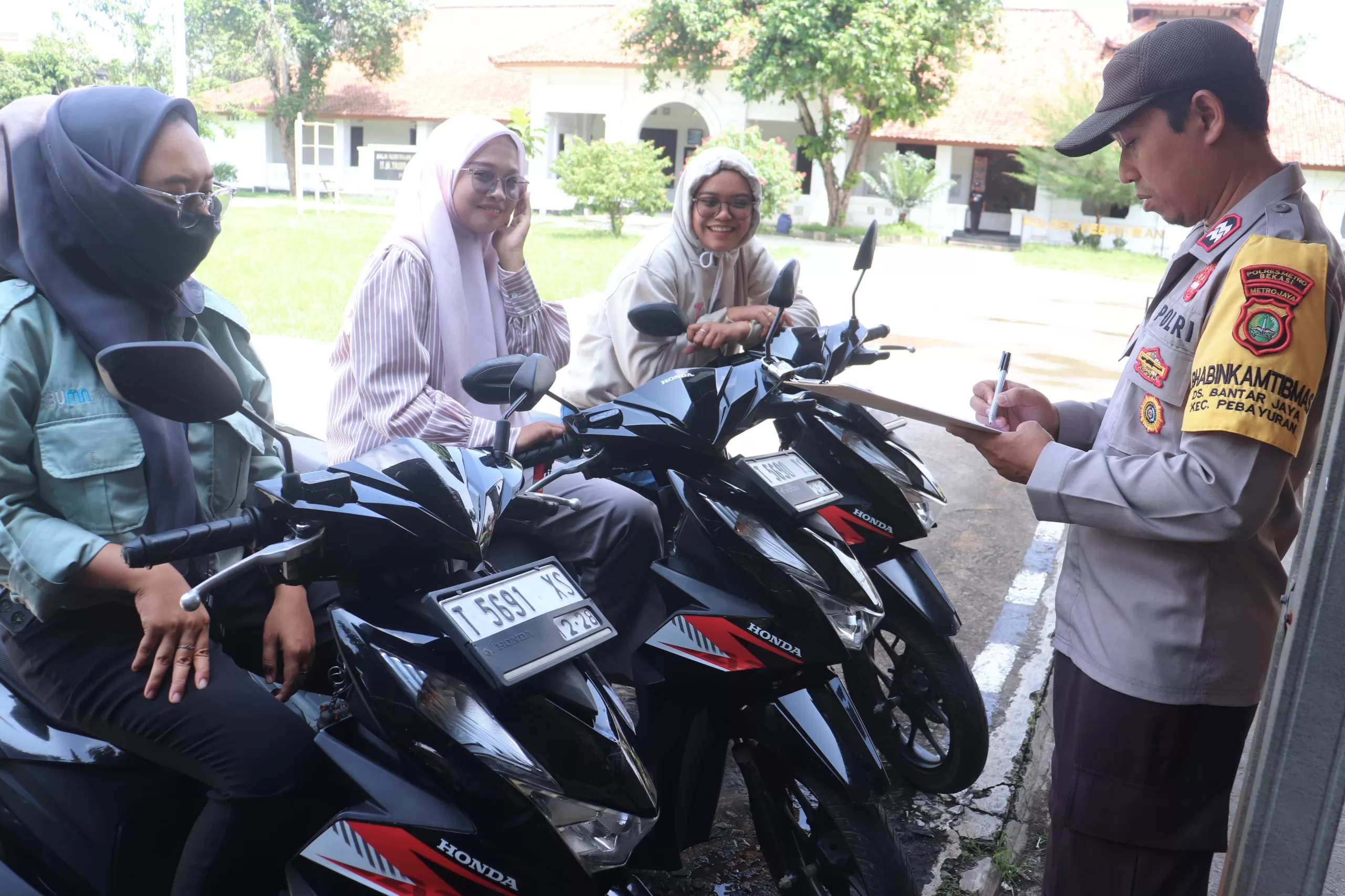 Petugas saat mendata kendaraan yang dititipkan secara gratis di Polsek Pebayuran