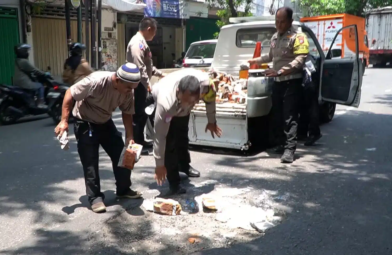 Anggota Kepolisian saat menambal jalan yang berlubang. (BM)
