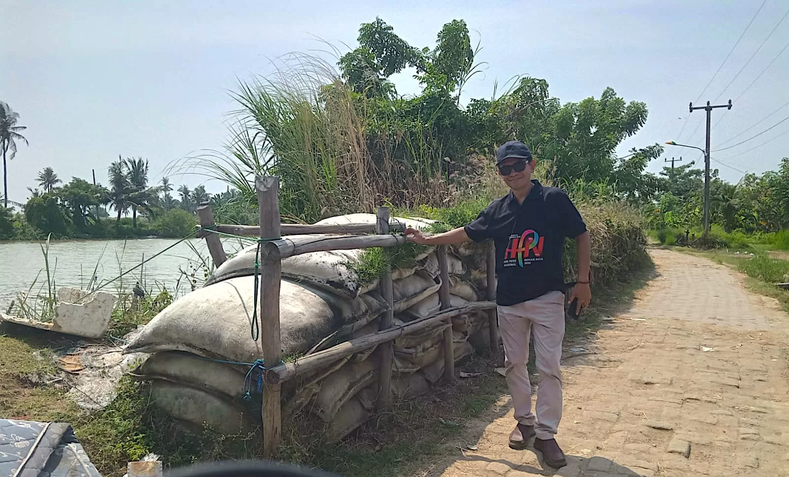 Ketua Panitia HPN Bekasi Raya 2025, tunjukkan kondisi tanggul yang dikeluhkan warga Desa Pantai Bahagia.