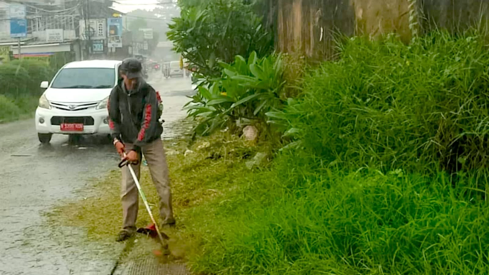 Salah satu petugas Kelurahan Jatiranggon saat memotong rumput di Jl. Hankam. (Pnd)