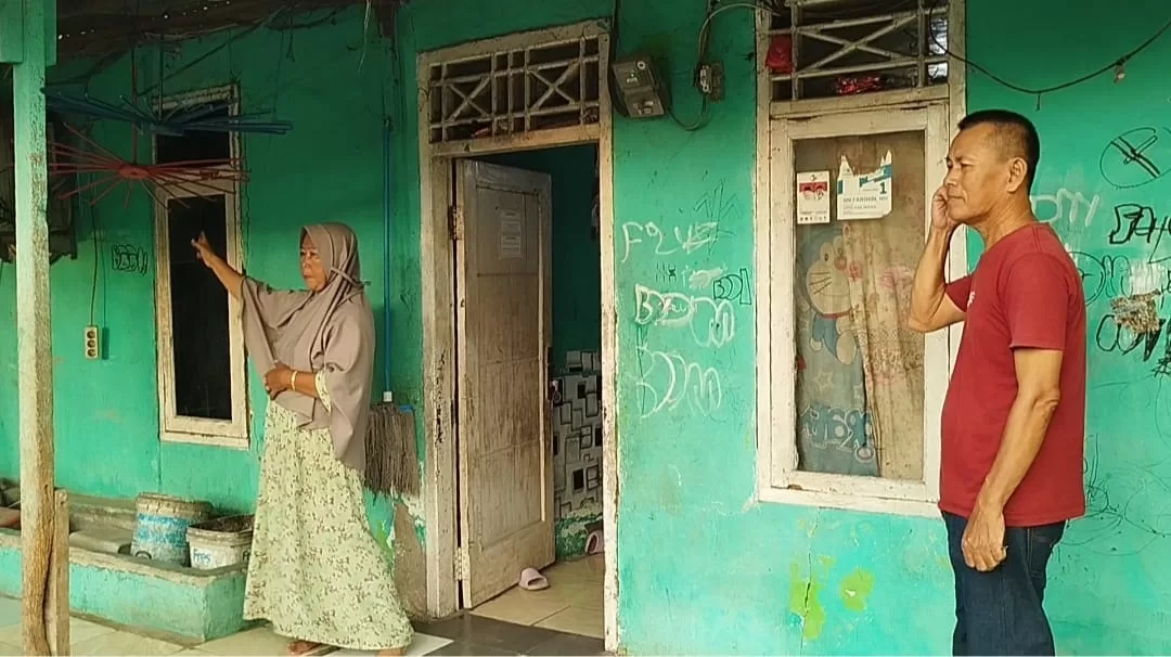 orang tua korban saat menunjukkan jendela yang dibobol oleh kawanan maling.