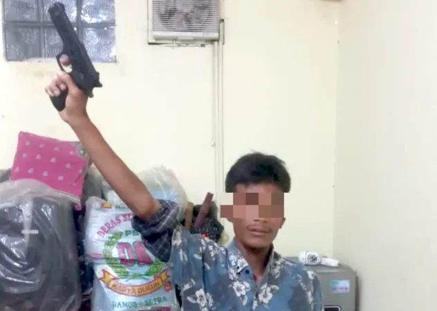 pria acungkan senjata mainan