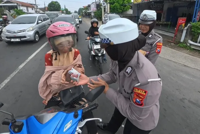 Polwan Satlantas Polres Pasuruan memberikan susu kepada pengendara tertib berlalu lintas (BM)