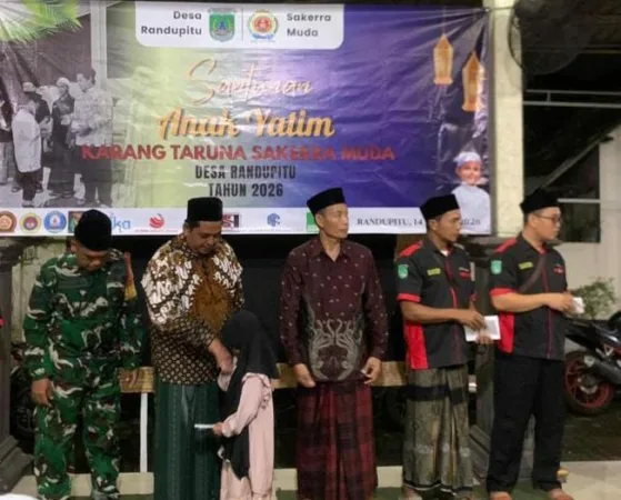 Ketua Karang Taruna bersama Kades Randupitu memberikan santunan anak yatim (BM)