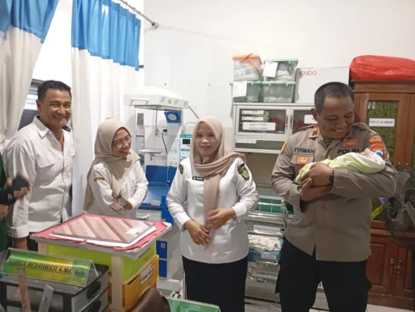Kapolsek Bangil Kompol Firman saat menggendong Bayi yang ditemukan warga di Puskesmas (hms)